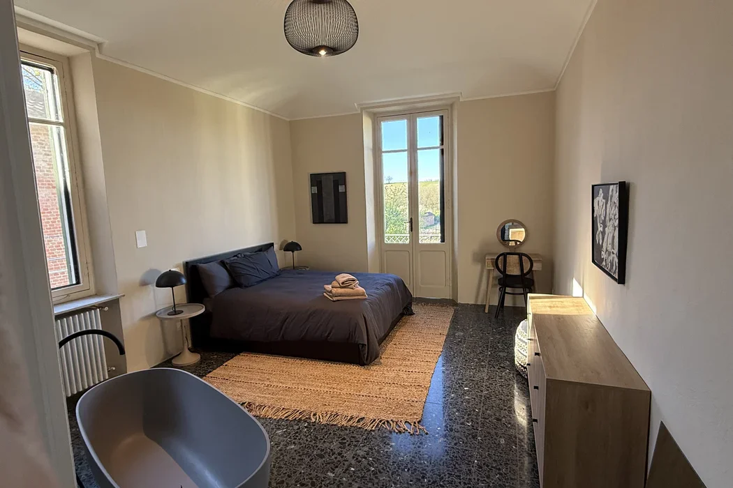 De master bedroom met vrijstaand bad en terrazzovloer
