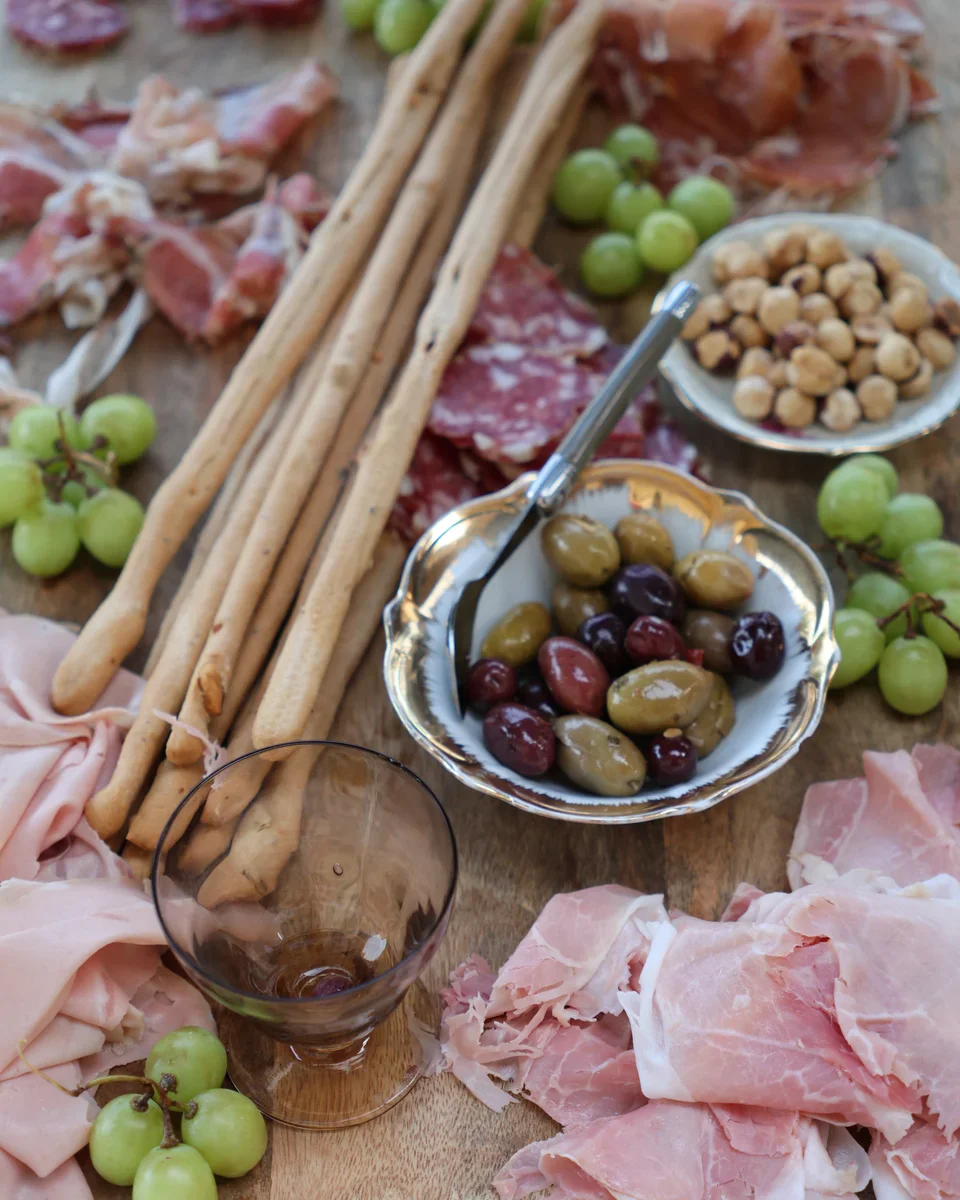 Een plank vol streekproducten: salumi, grissini, olijven.